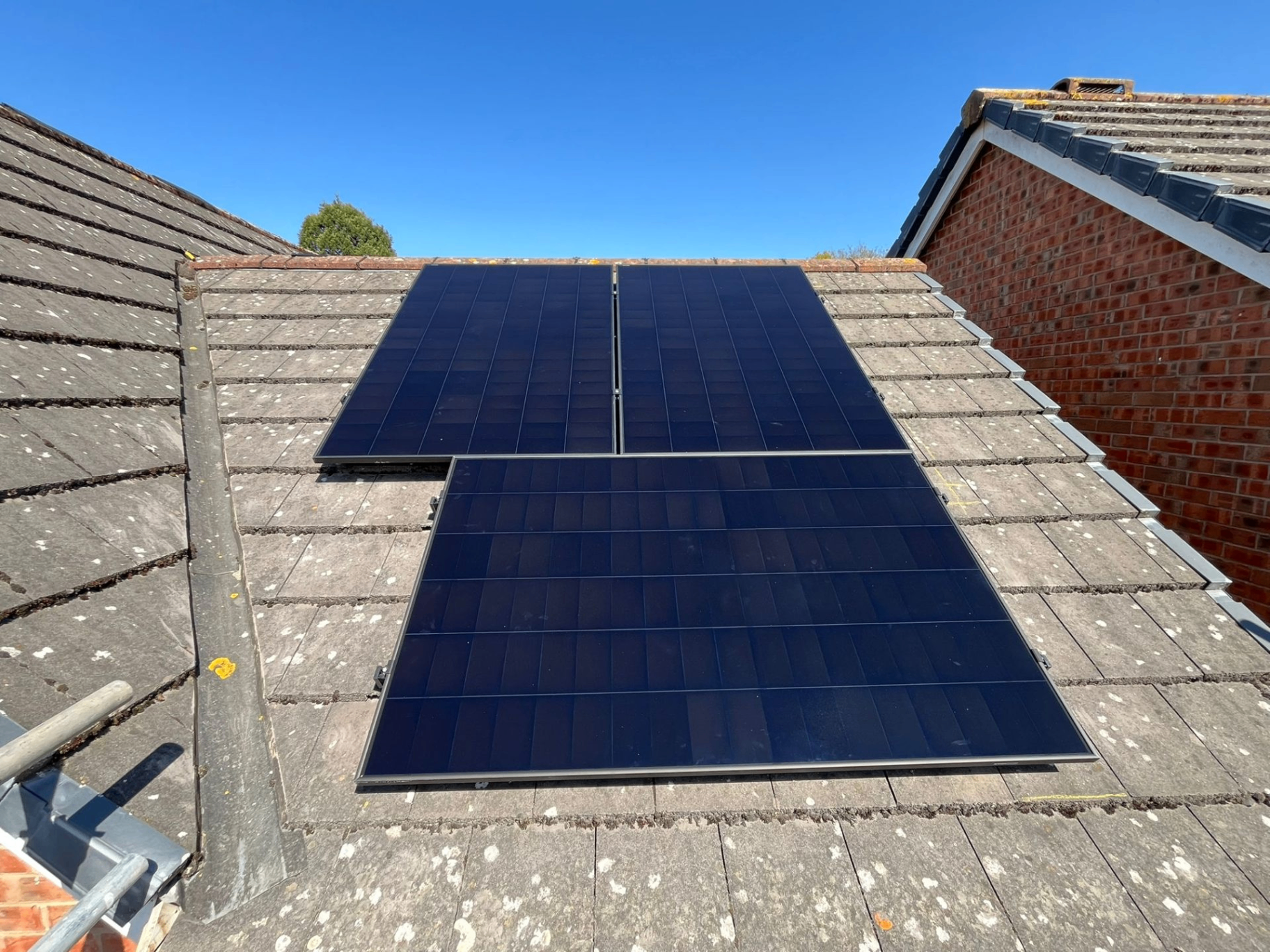 Small domestic solar array installed cleanly on a tiled roof under a bright blue sky