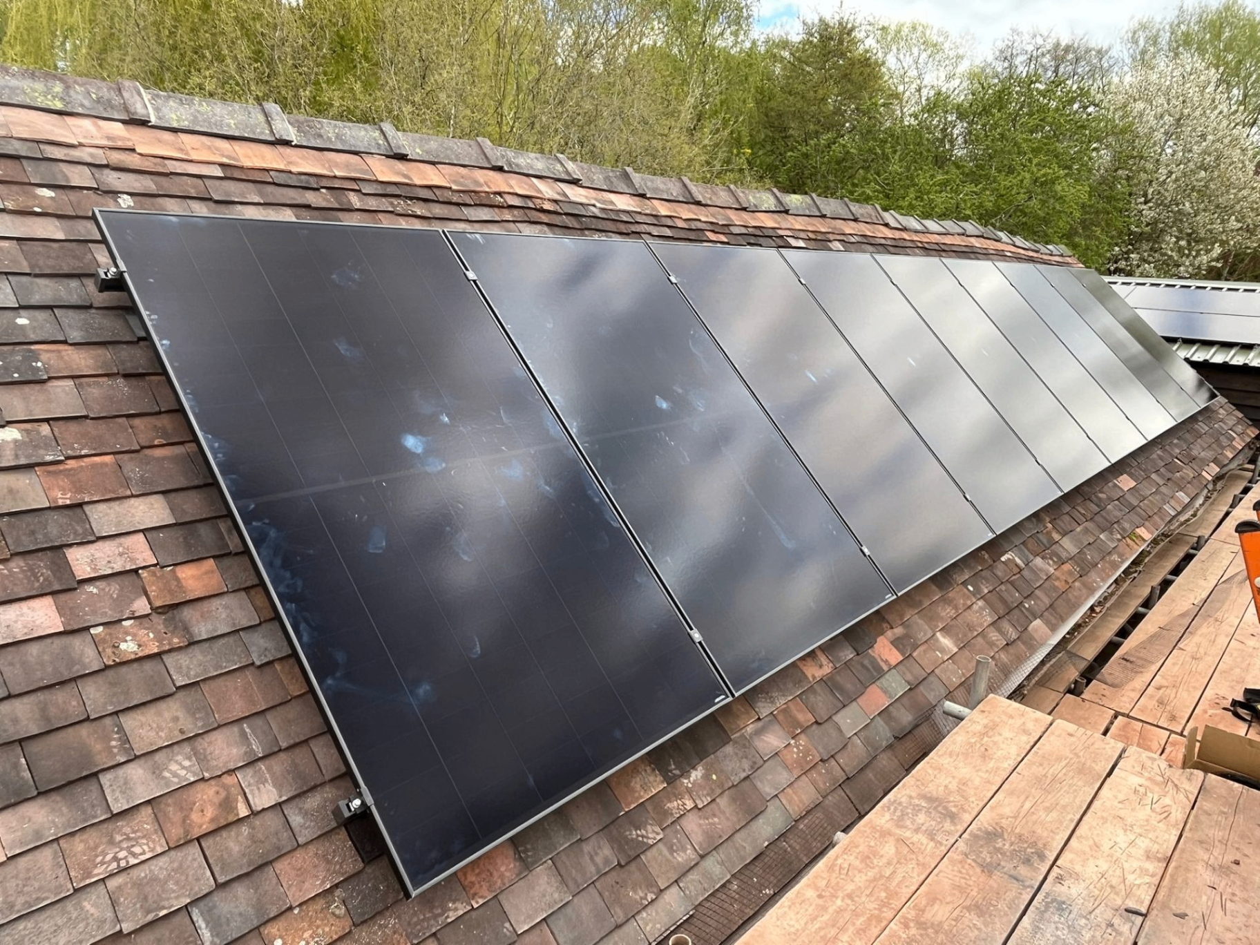 Long run of black solar panels installed on a pitched tiled roof during a recent job