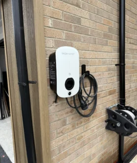 OZEV-approved home EV charger cable run clipped along an exterior wall