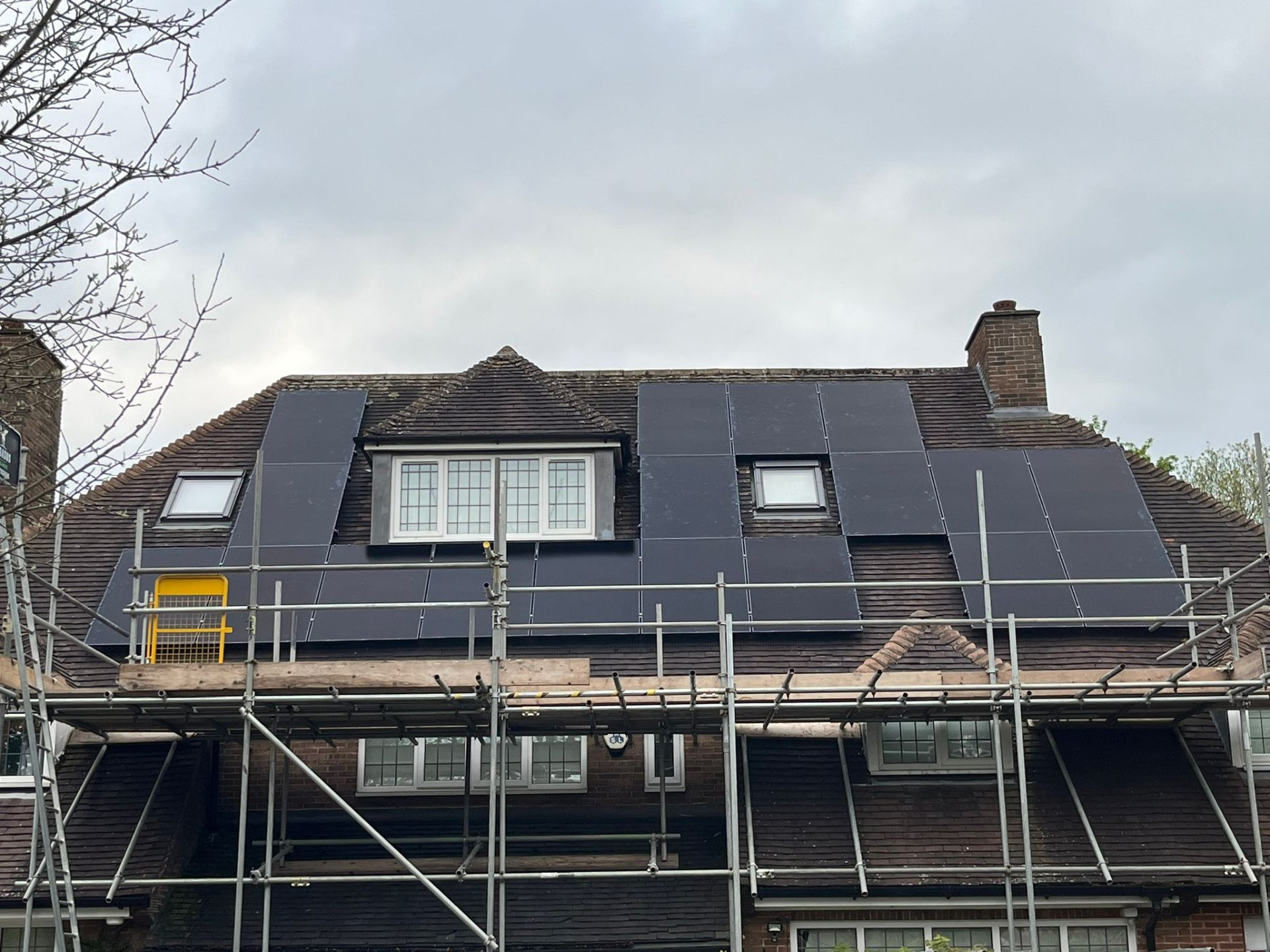 Completed multi-array solar panel installation on a large house with scaffolding in place