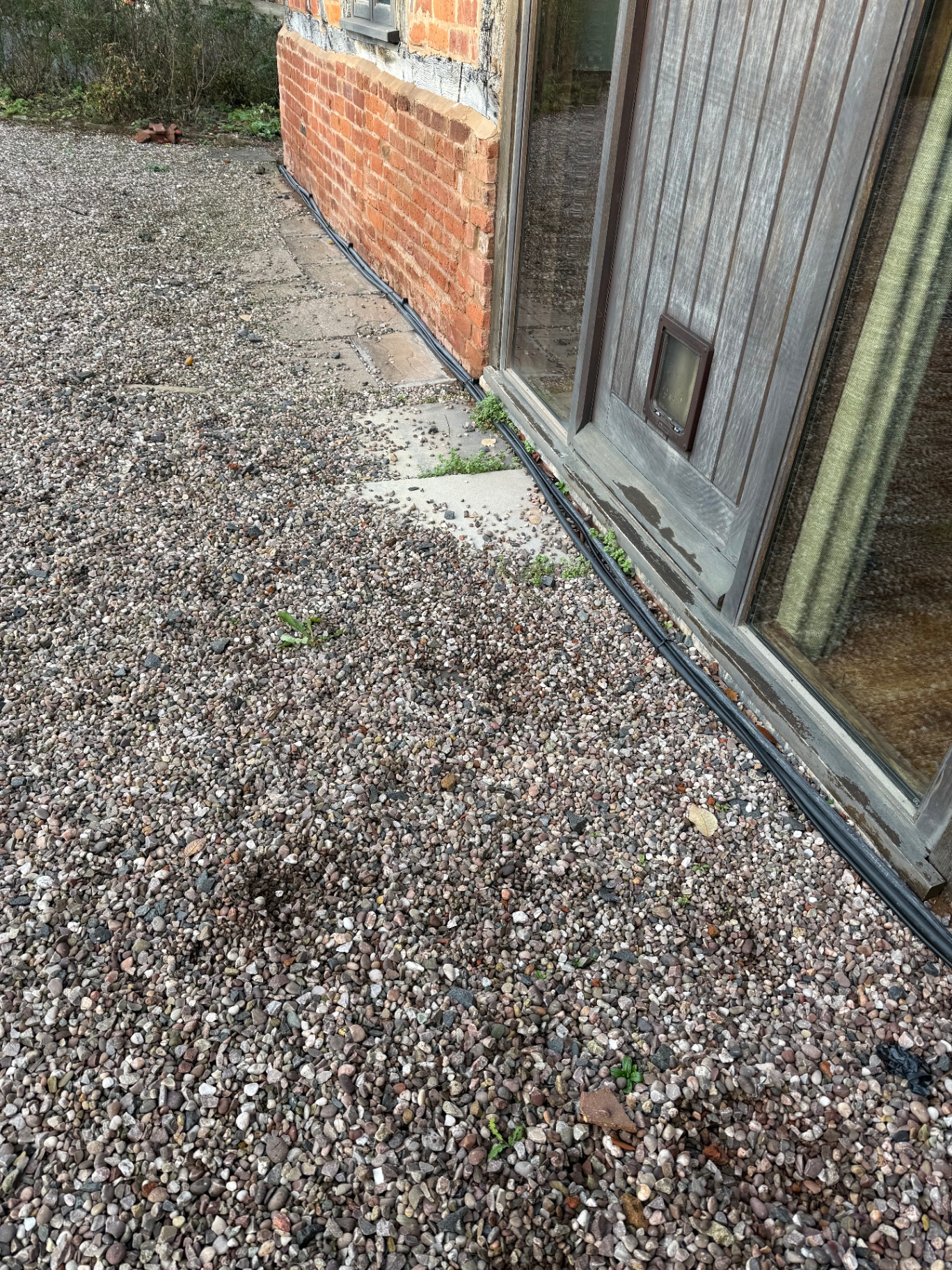 Neatly clipped EV charger cable run along an external UK brick wall